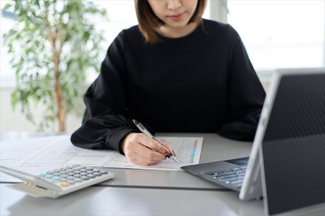 電卓と書類を使い会計入力を行う様子